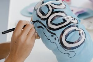 Halloween Letter Board Quotes Close Up of a Person Painting a Pumpkin Blue with the Word "Boo" on it