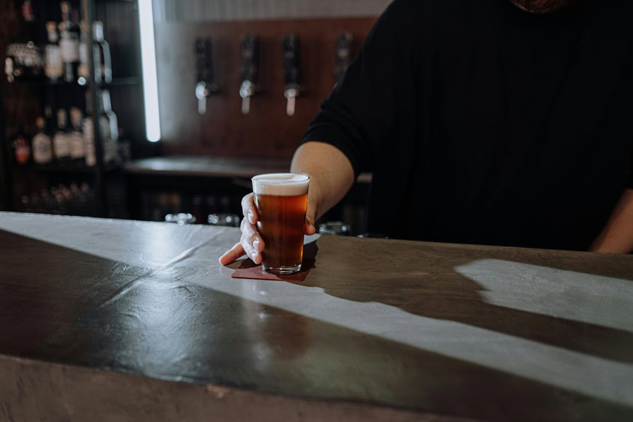 Things to Know About Craft Beer Close Up of a Person's Hand Holding a Glass of Craft Beer on a Bar Top