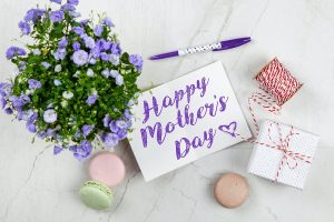 Mother's Day Brunch Decor Ideas Overhead View of a Card That Says Happy Mother's Day Next to Flowers and French Macarons