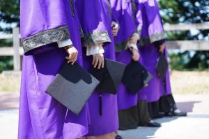 Graduation Gift Ideas Close Up of a Line of Graduates Holding Their Graduation Caps in Their Right Hands